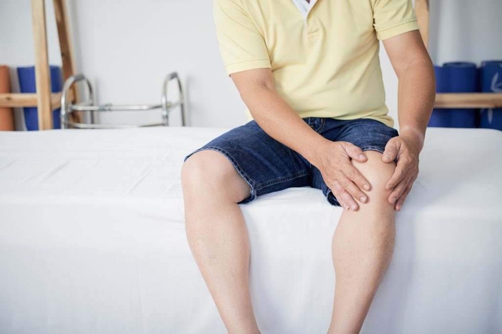 Crop man touching aching knee